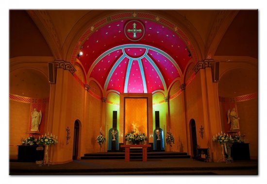 Interior of a historic wedding chapel in Beaver Dam, WI, featuring a vibrant magenta domed ceiling with a central cross above an altar decorated with floral arrangements.